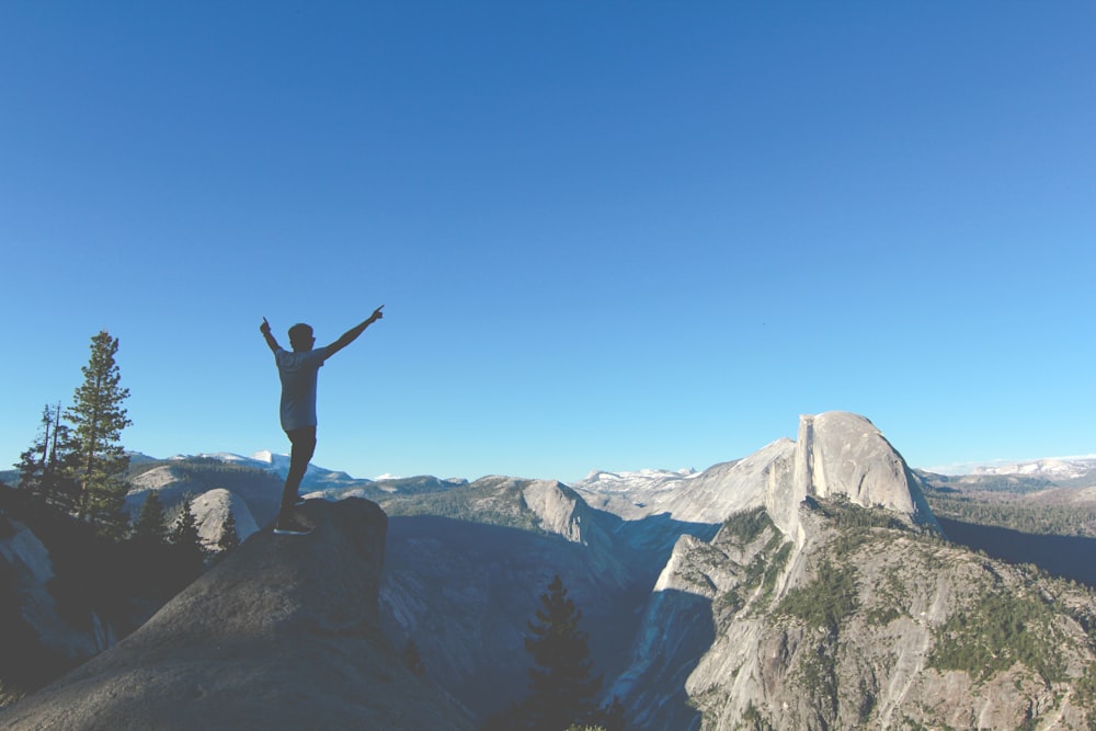 person standing on rock hands up