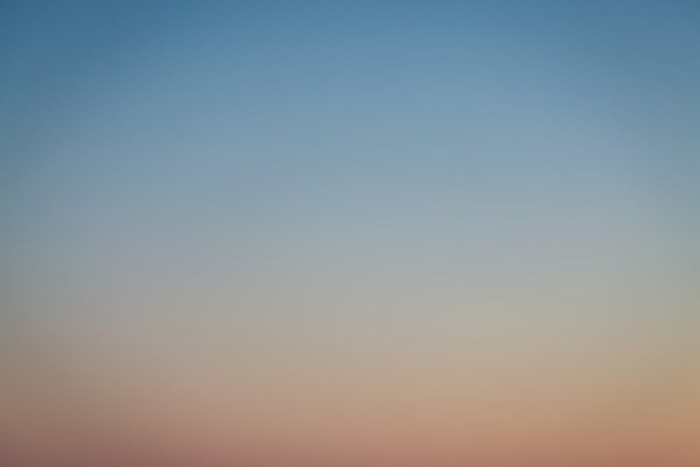 a plane flying in the sky at sunset