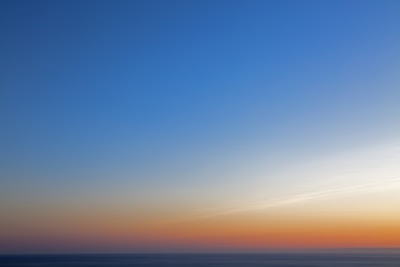 A calm blue horizon blending into a golden sky, evoking peace, elevation, and clarity.