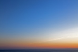 A calm blue ocean horizon meeting a bright sky at sunrise.