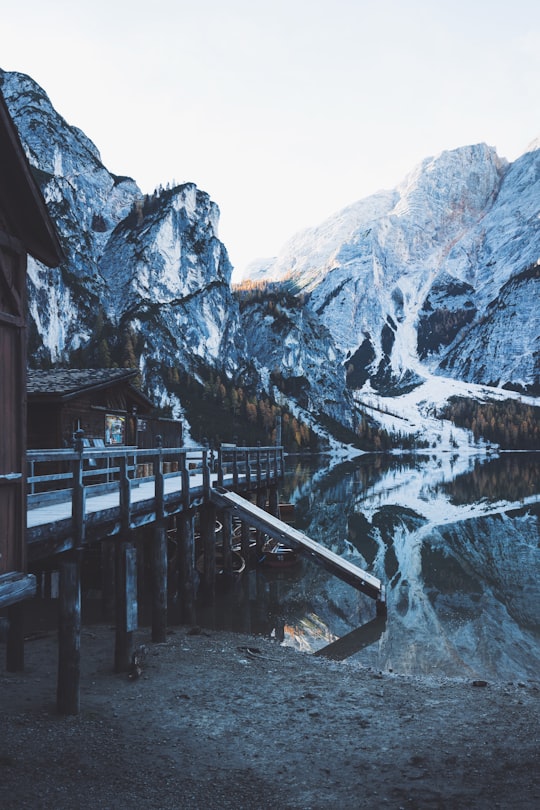 brown wooden bridge near river and snow-capped mountains at daytime in Parco naturale di Fanes-Sennes-Braies Italy