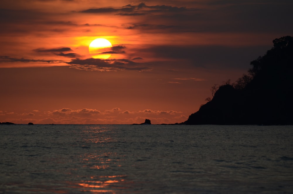 rock formation surrounded by water during sunset