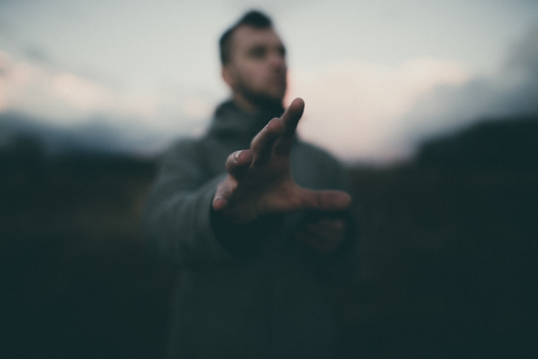 man in gray jacket raising his hand