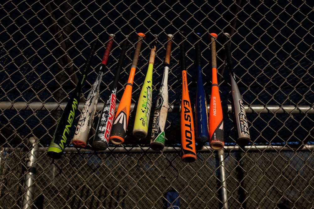 bates de béisbol colgados en la cerca del campo