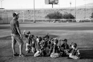 grayscale photo of boys football team in front of coach