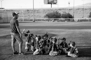 grayscale photo of boys football team in front of coach