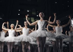 group of ballerinas dancing while raising both hands