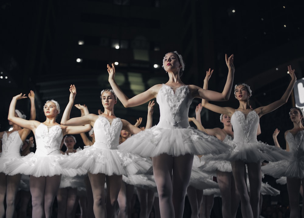 Gruppe von Ballerinas, die tanzen, während sie beide Hände heben
