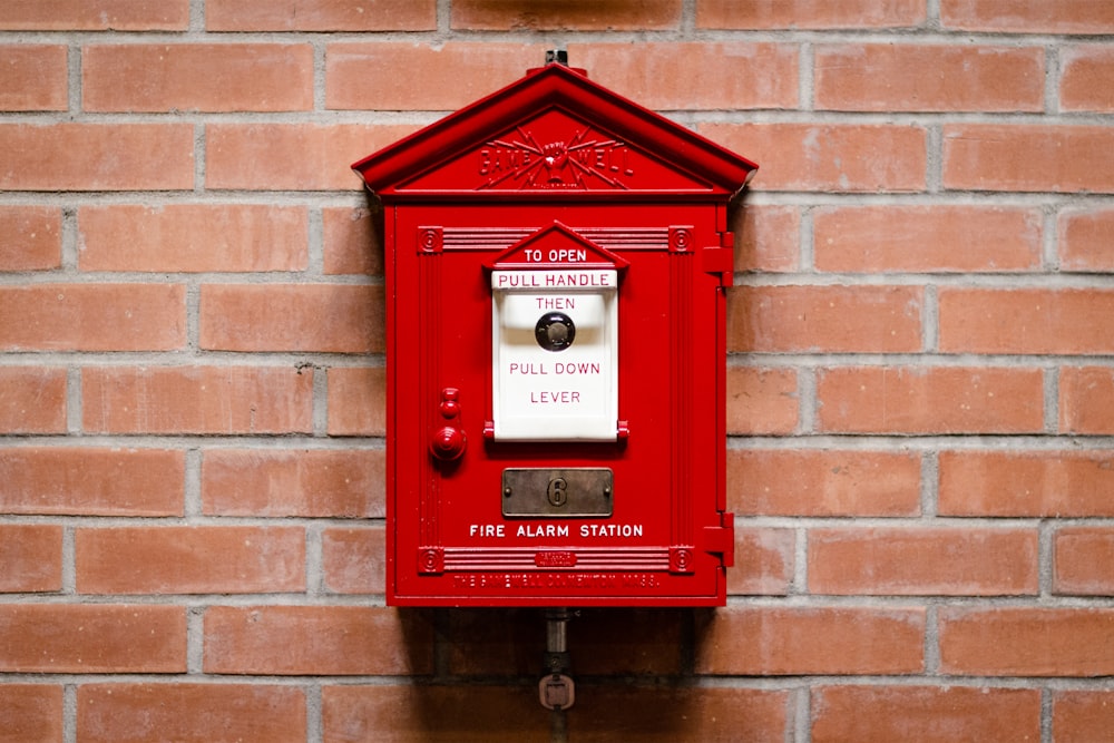 Poste d’alarme incendie rouge fixé sur un mur de briques