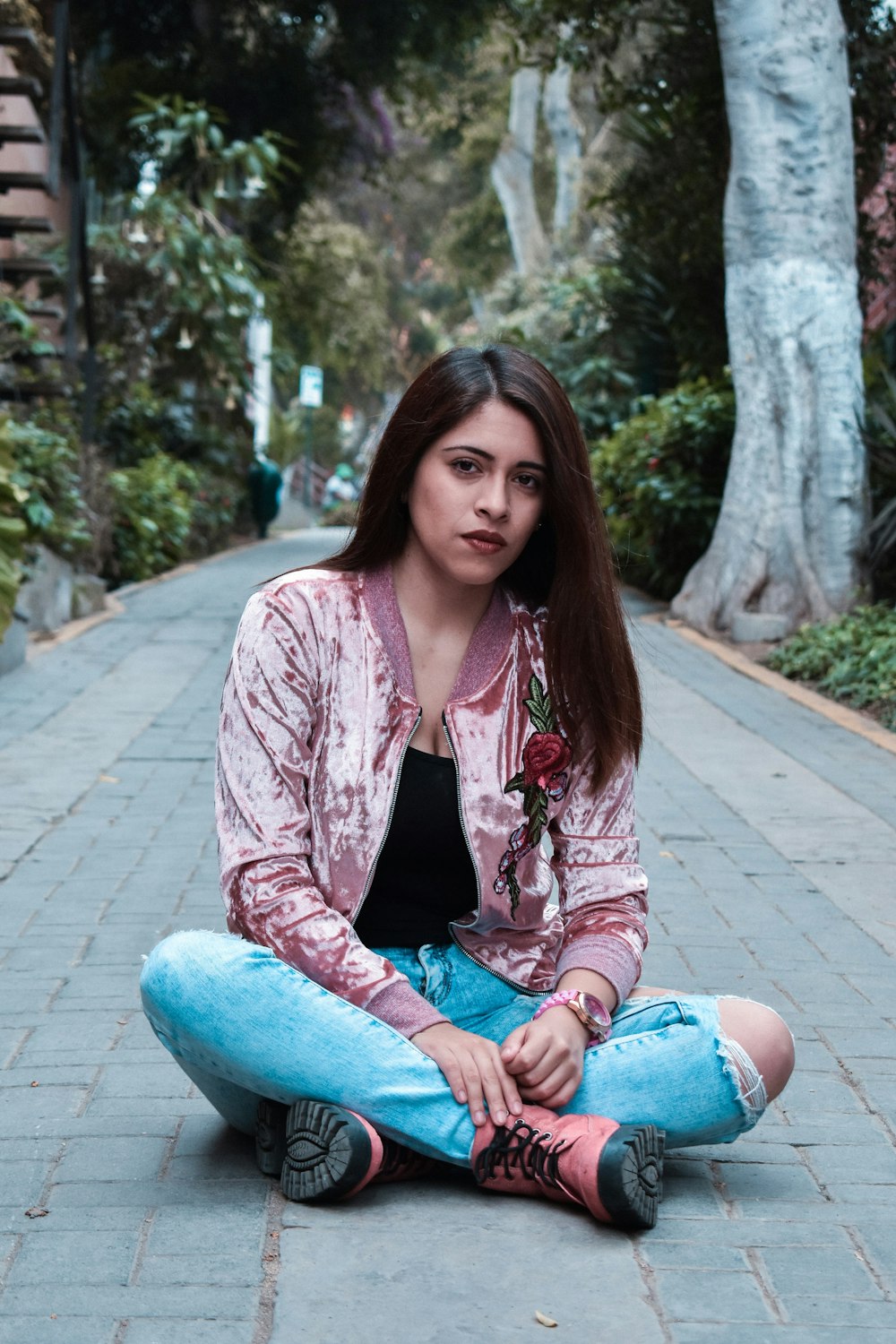 woman sitting on ground in between trees at daytime