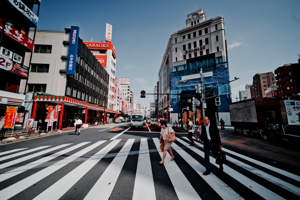 people crossing on pedestrian lane near buildings