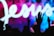 A silhouette of a person raising their hand in front of a vibrant background featuring the word 'Jesus' in large, flowing white script. The background displays a mixture of blue, pink, and purple hues.