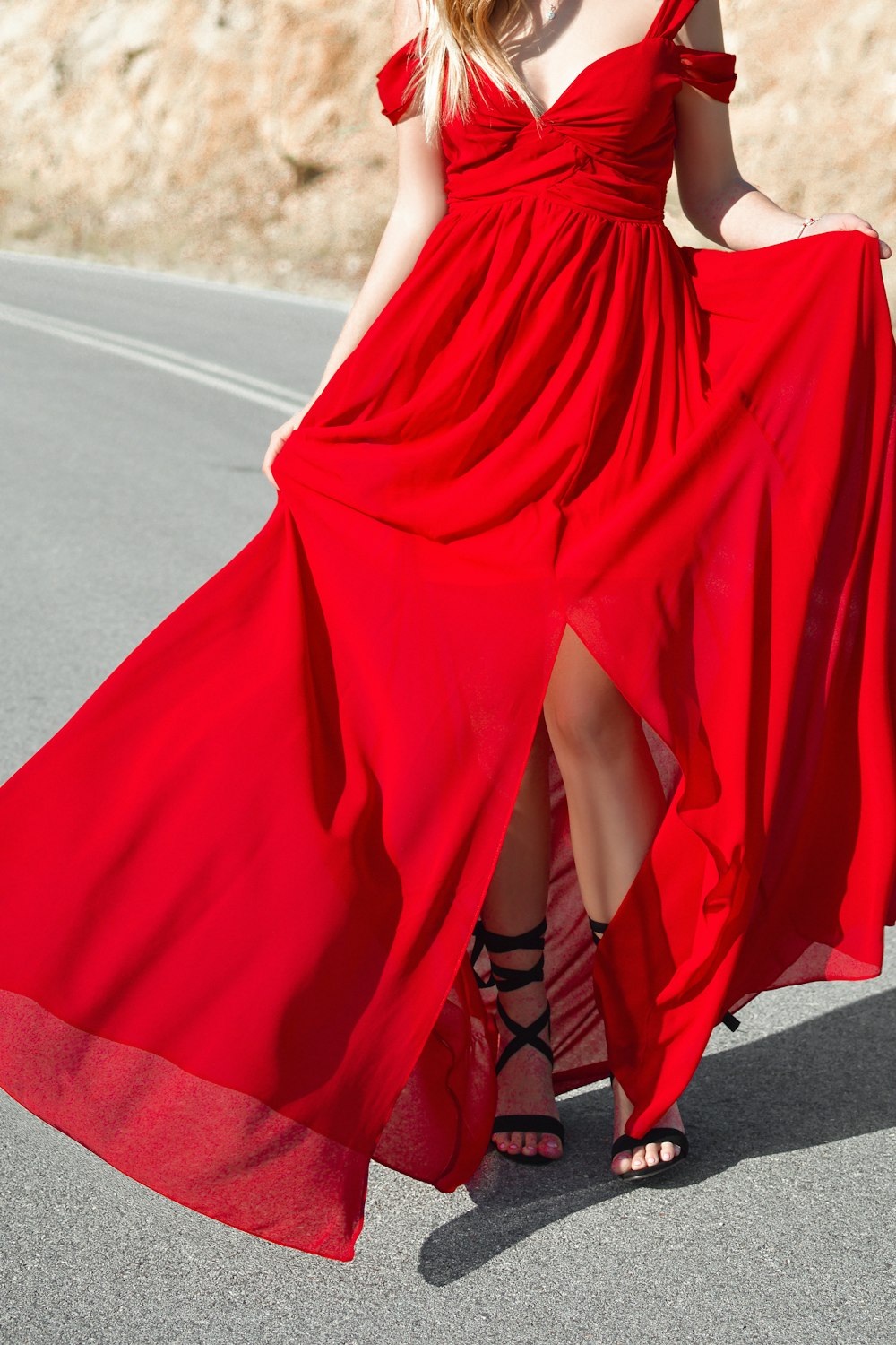 mujer con vestido formal rojo con abertura frontal de hombros fríos de pie en el camino