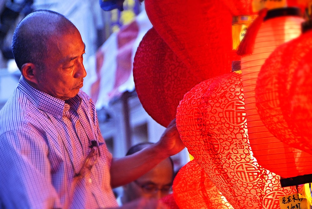 homme tenant des lanternes rouges pendant la journée
