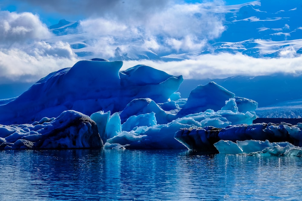 iceberg accanto alla scogliera sotto il cielo nuvoloso durante il giorno