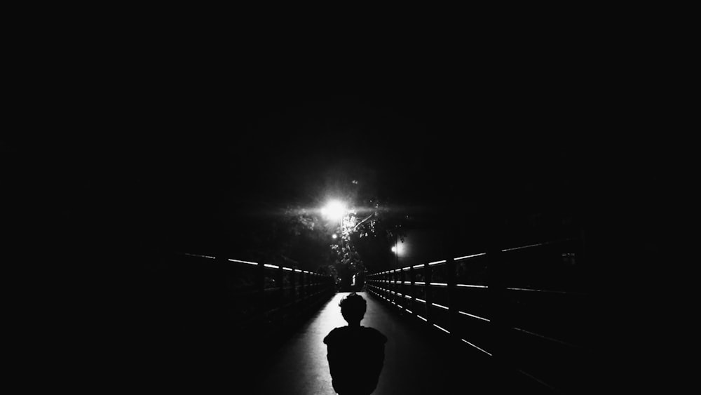silhouette photo of child standing on bridge