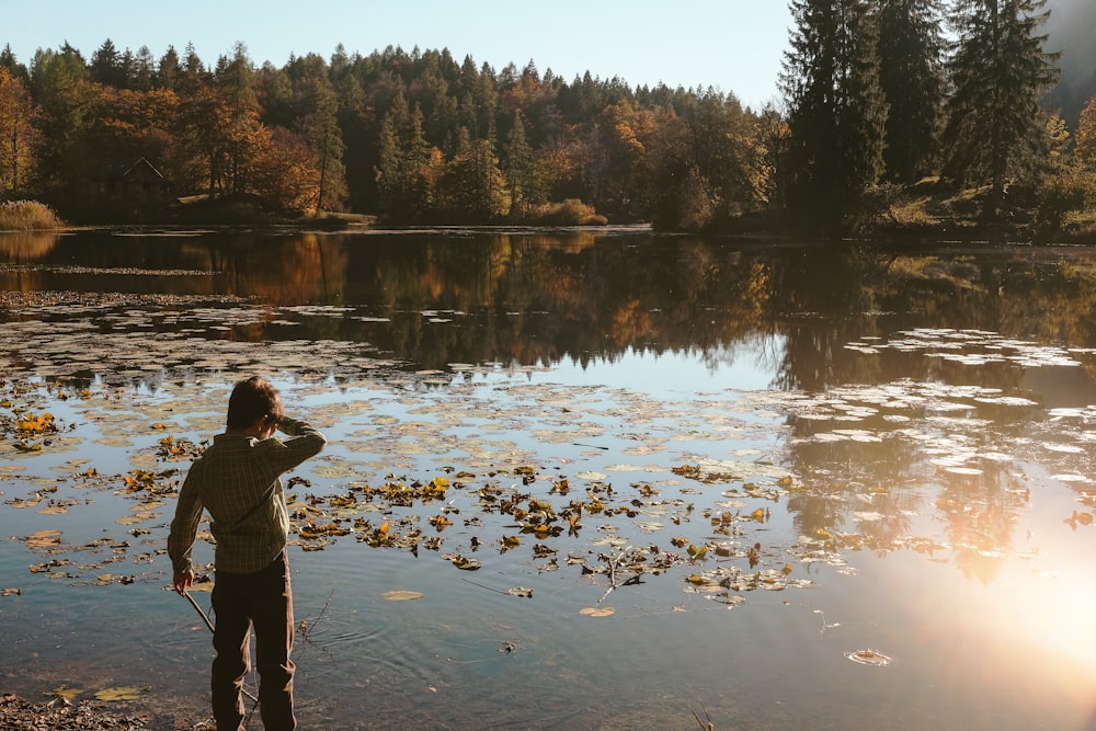 boy standing beside body of water during daytime