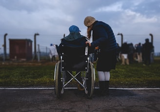woman standing near person in wheelchair near green grass field