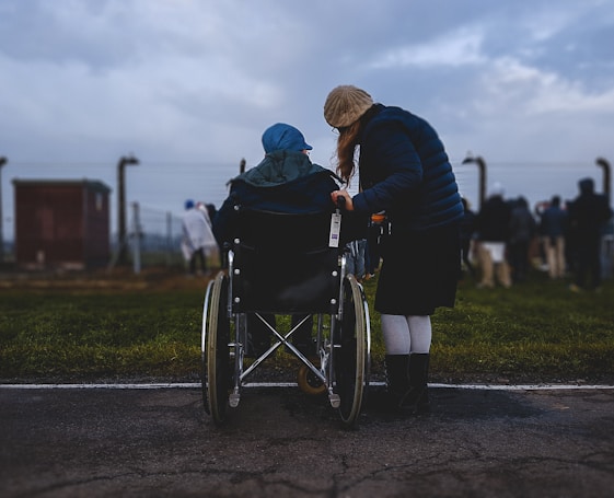 woman standing near person in wheelchair near green grass field