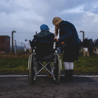 woman standing near person in wheelchair near green grass field