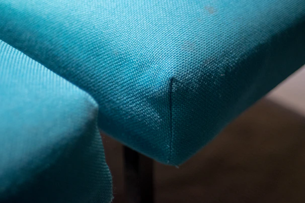 Close-up of precise stitching on a muted teal tailored dress, highlighting the premium fabric texture and clean lines.