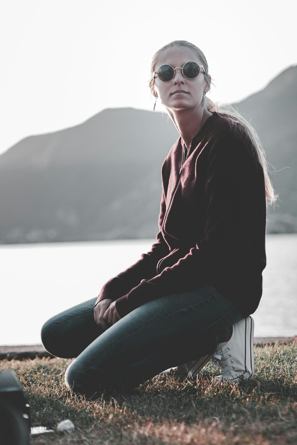 shallow focus photography of woman kneeling at the grass looking side ways