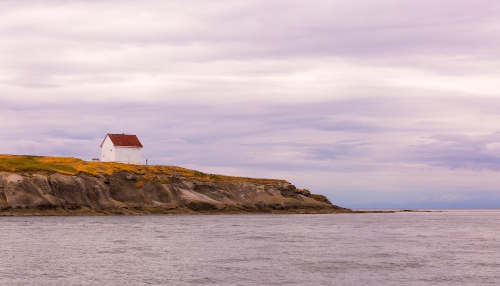 Maison en bois blanc et rouge près de la mer pendant la journée