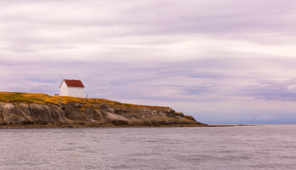 Casa de madeira branca e vermelha perto do mar durante o dia