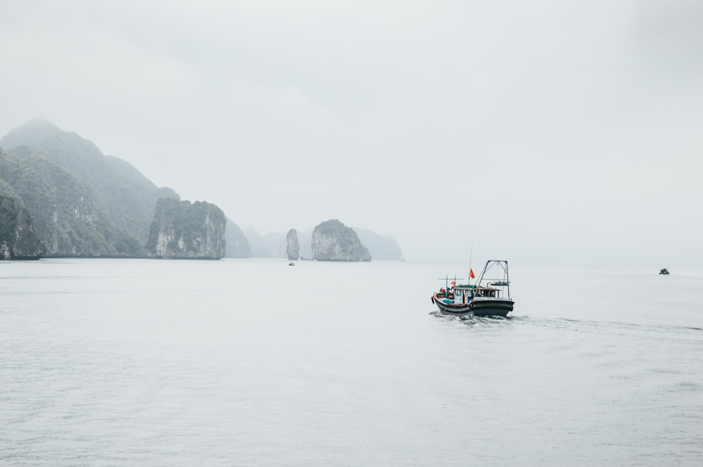 Bateau noir et blanc près d’une formation rocheuse