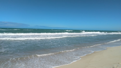 A serene beach with a clear blue sky and gentle waves.