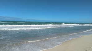 A serene beach with gentle waves and a clear sky.