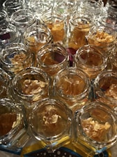 Close-up of glass jars filled with golden honey on a rustic wooden table with honeycombs nearby.