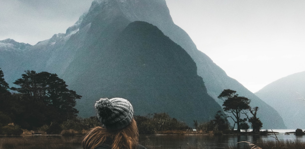 woman sitting near body of water looking at clouds