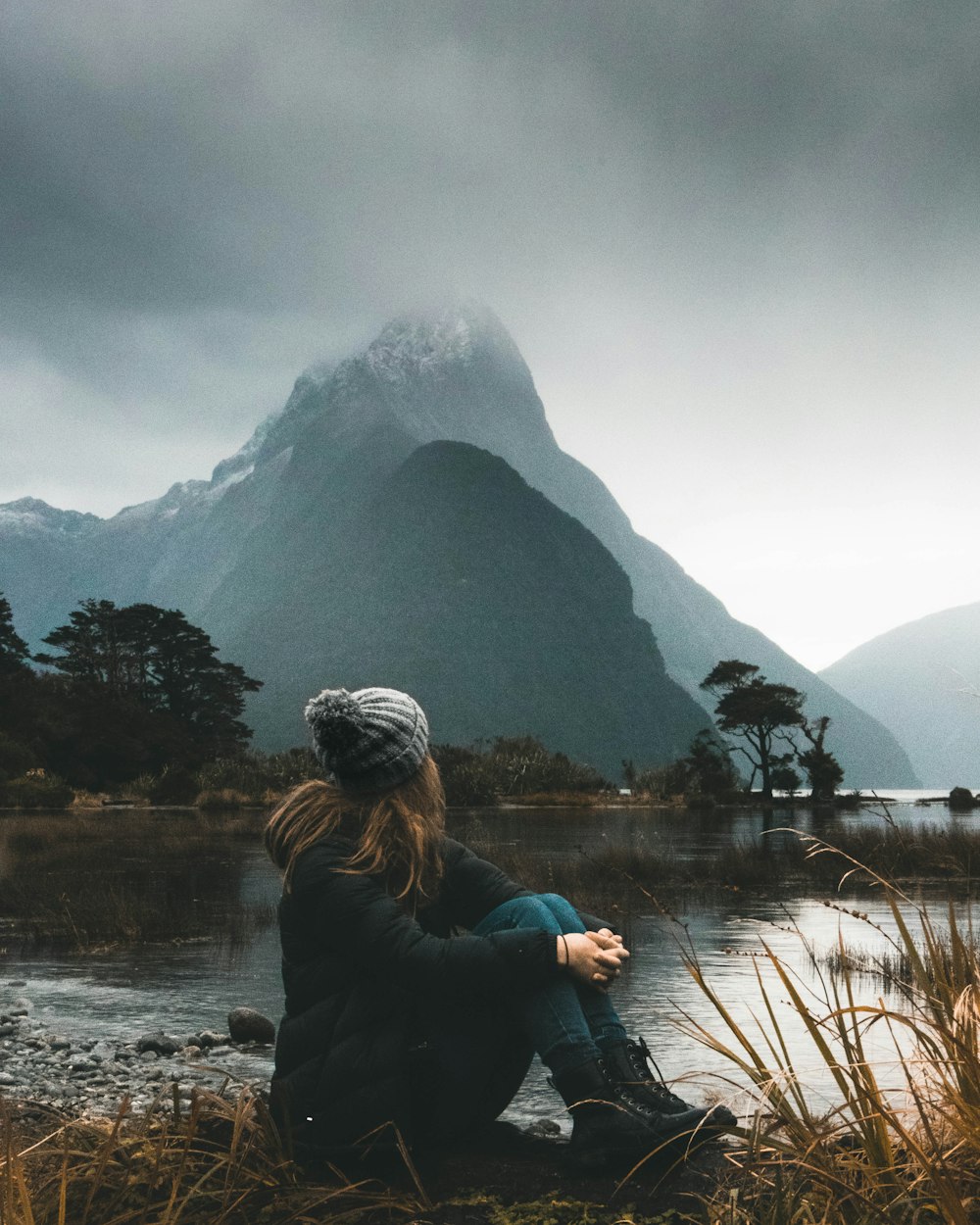 Mujer sentada cerca de la masa de agua mirando las nubes