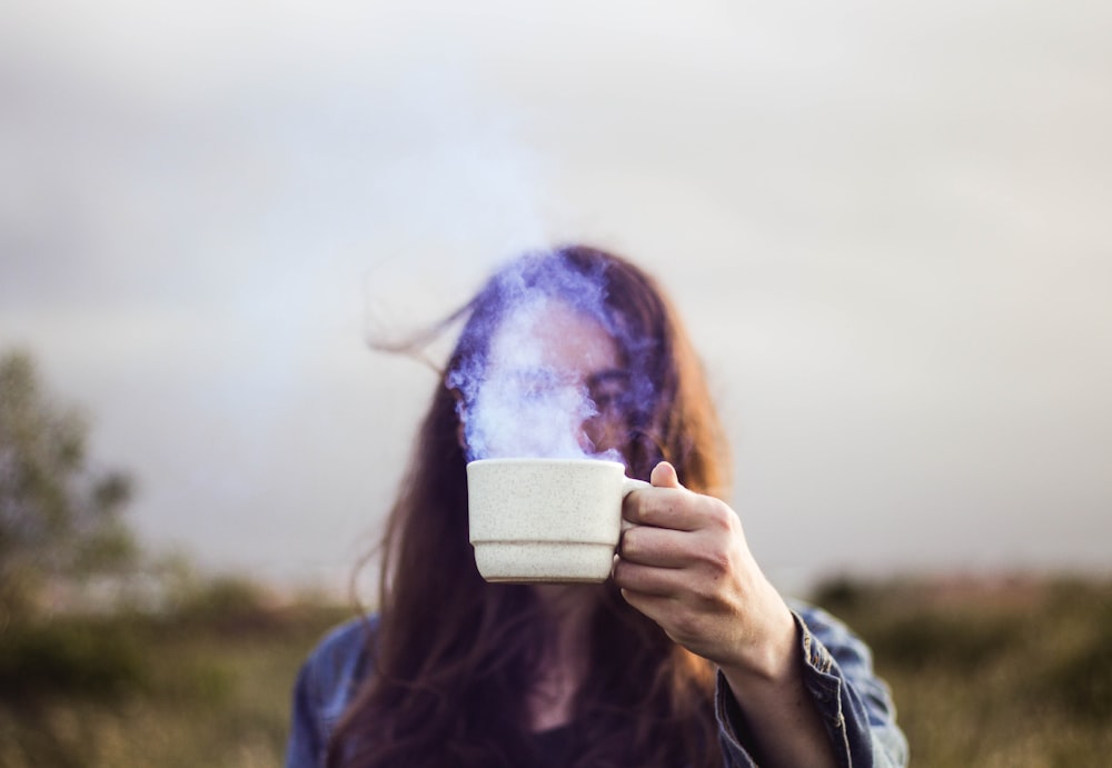 Foto de foco seletivo do homem segurando a xícara de café de cerâmica branca
