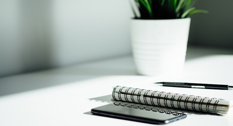 pen, notebook, and smartphone on a clean white table 