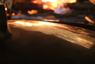 A reflective surface catching the glow of fiery brushstrokes in a contemplative artwork.