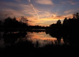 A serene outdoor scene captured through a camera lens, showing a sunset over a quiet lake.