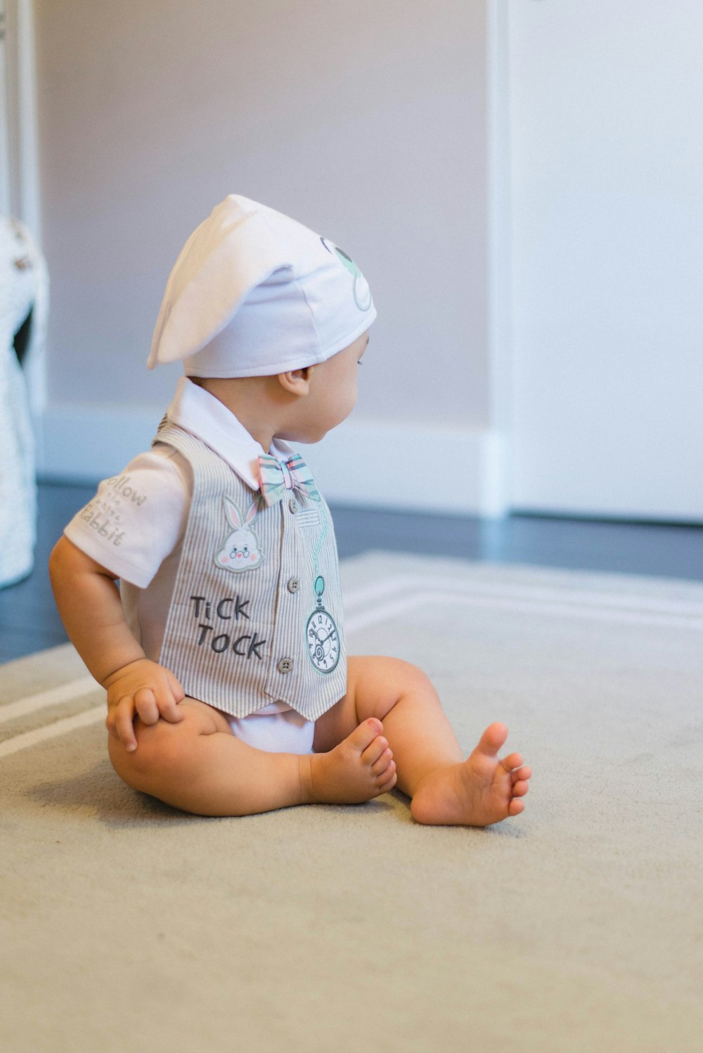 baby sitting on gray area rug inside room