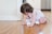 Close-up of a baby crawling on a colorful play mat wearing a diaper