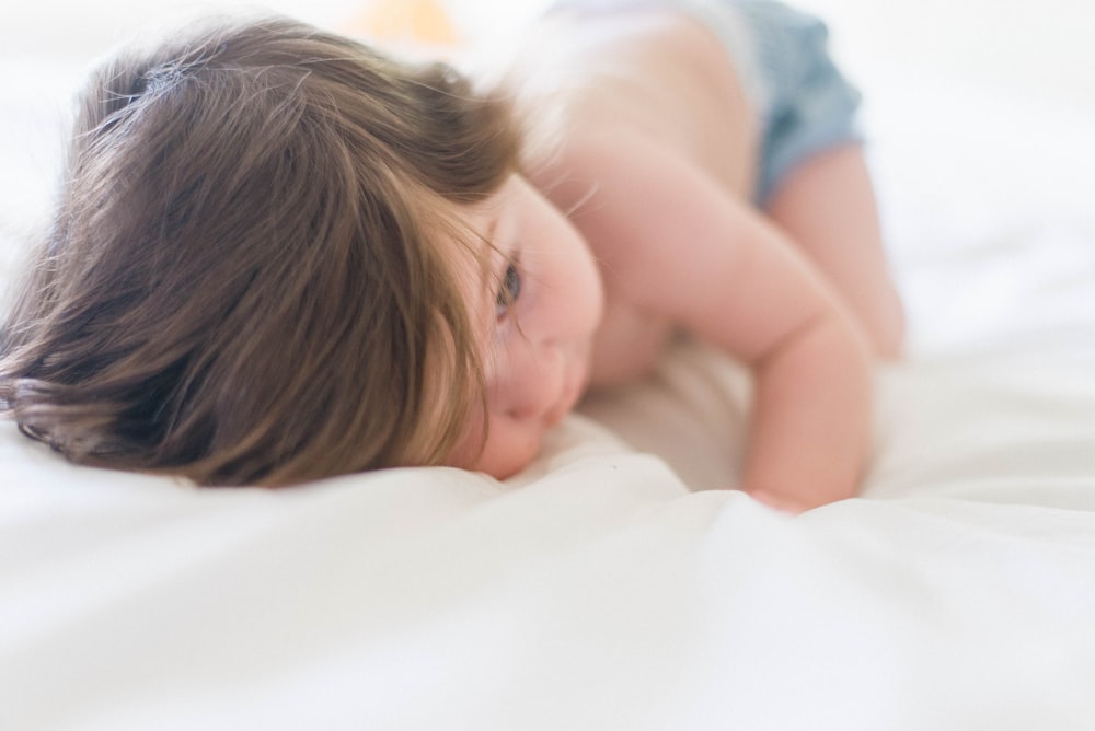 baby laying on white surface