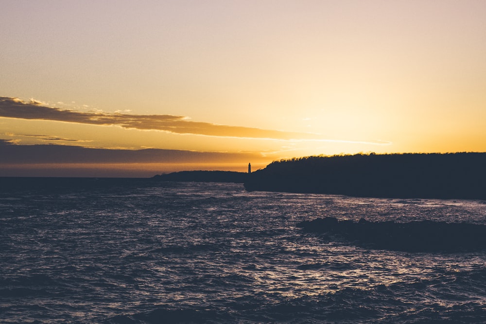 silhouette of cliff and body of water