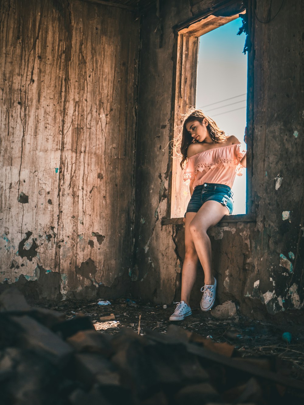 Femme en chemisier rose assise sur la fenêtre