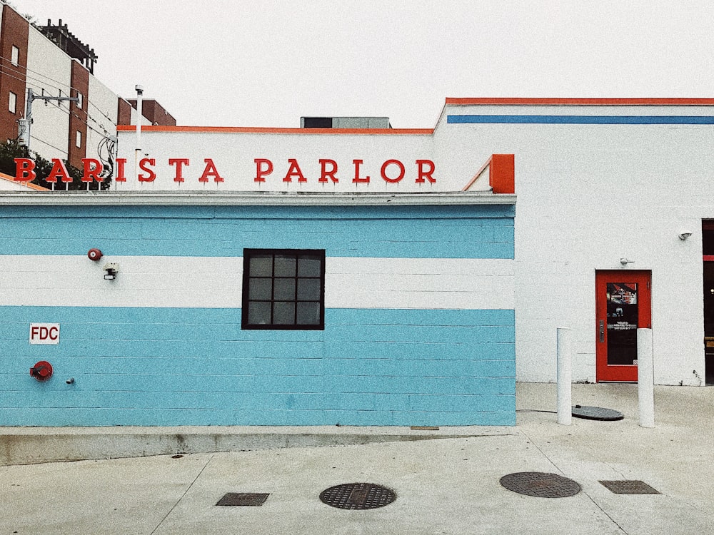 바리스타 팔러 간판이 있는 흰색과 파란색으로 칠해진 콘크리트 건물