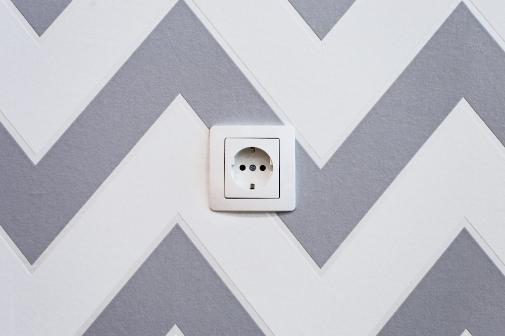 white power strip mounted on white and grey chevron painted wall