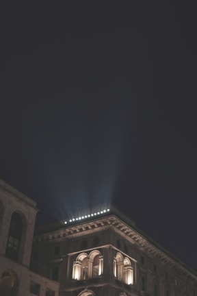 Exterior view of the building at night, illuminated with warm golden lights against a dark sky.