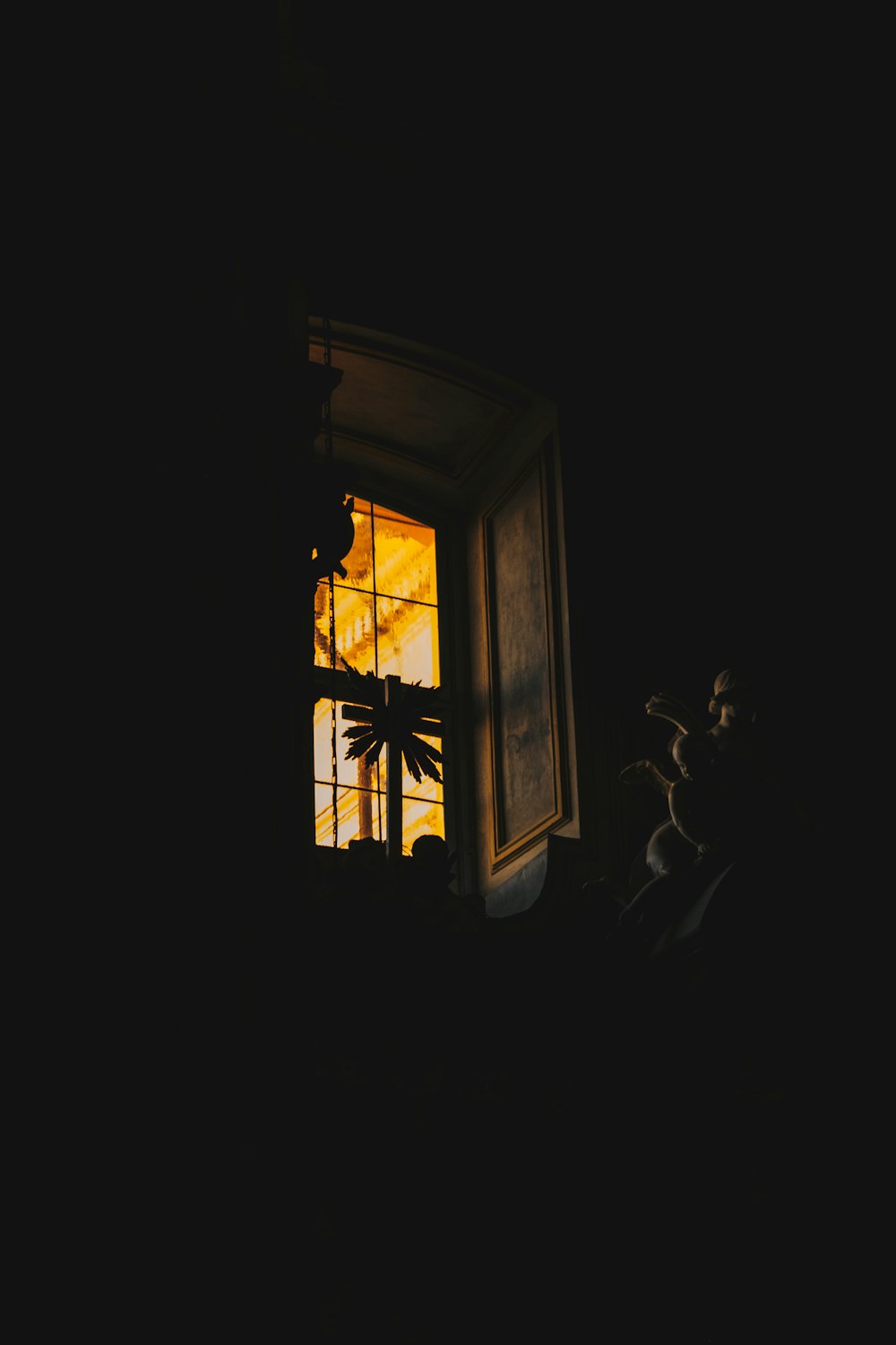 a window in a dark room with a palm tree outside