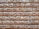 A wall constructed with alternating layers of red bricks and irregularly shaped gray stones, set in light gray mortar, creating a rustic and textured appearance.