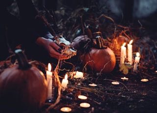 person decorating pumpkin and candles