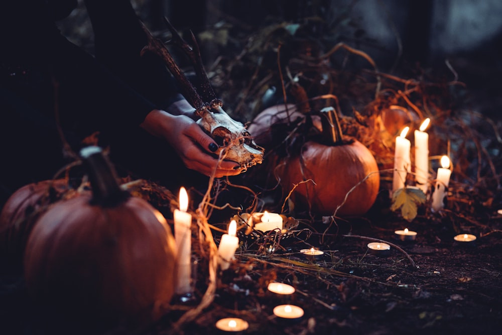 person decorating pumpkin and candles